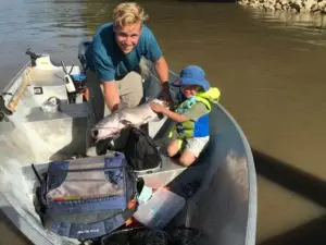 A woman and child in a boat with luggage.