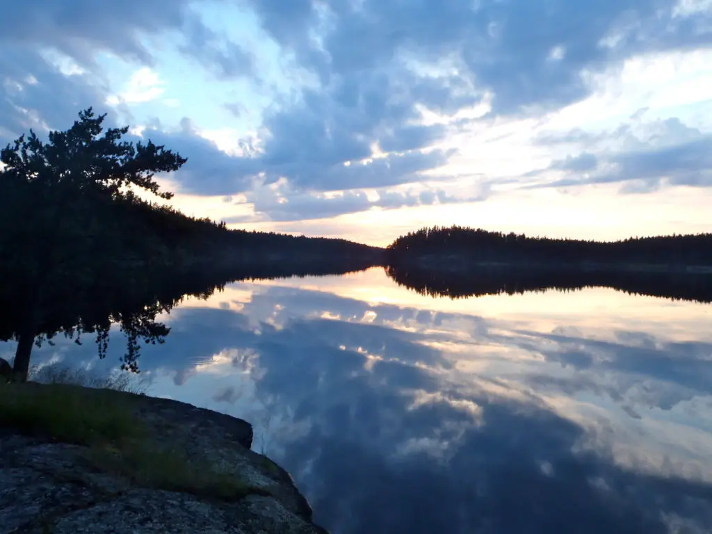 A body of water with trees and clouds in the sky.