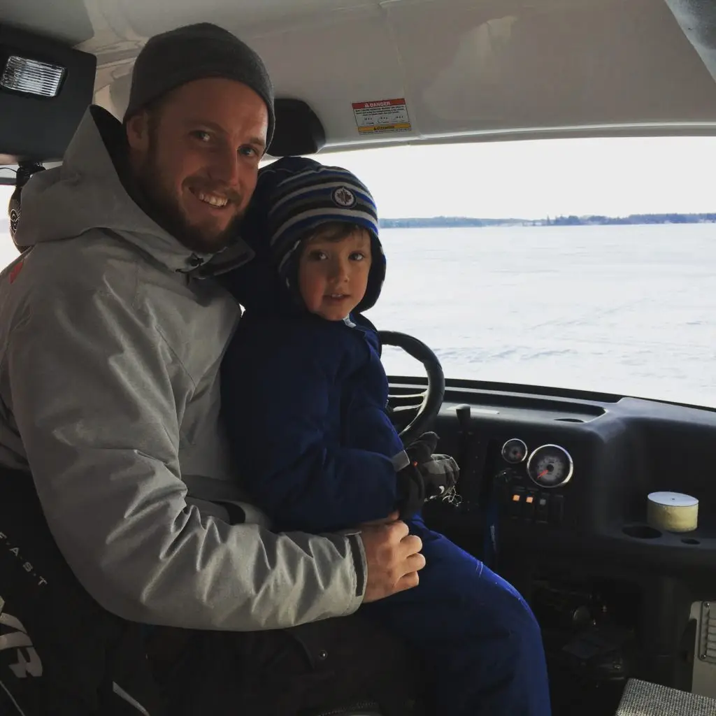 A man and boy in the driver 's seat of a car.