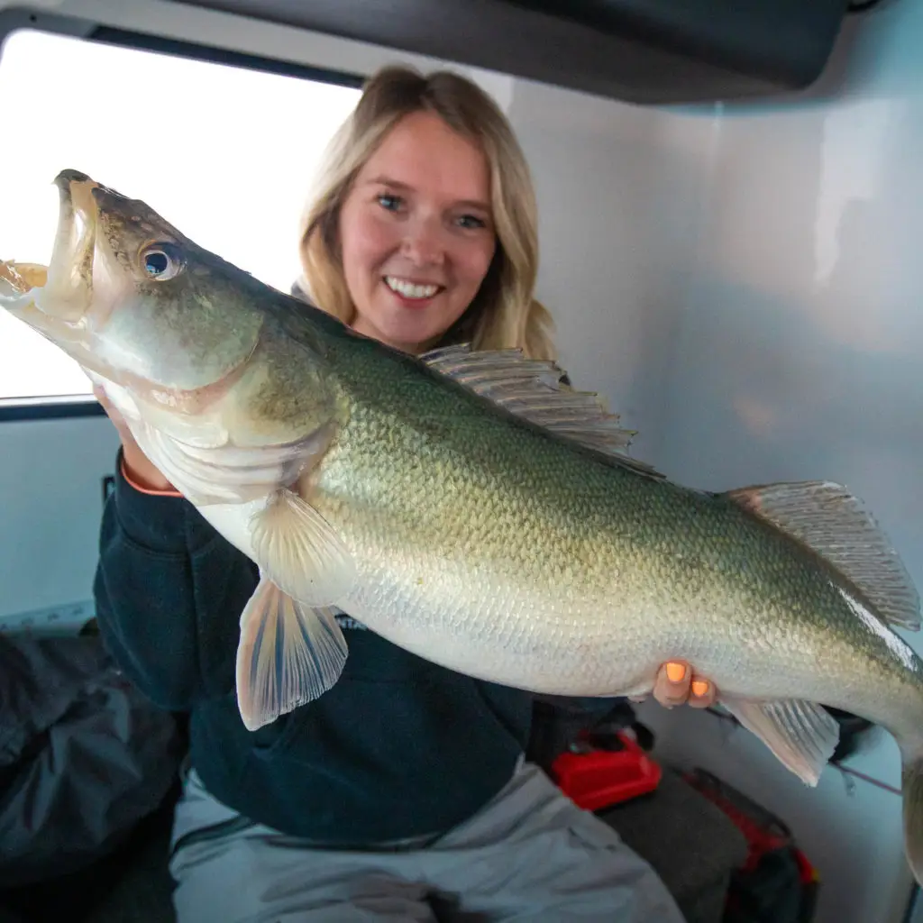 A woman holding a large fish in her arms.