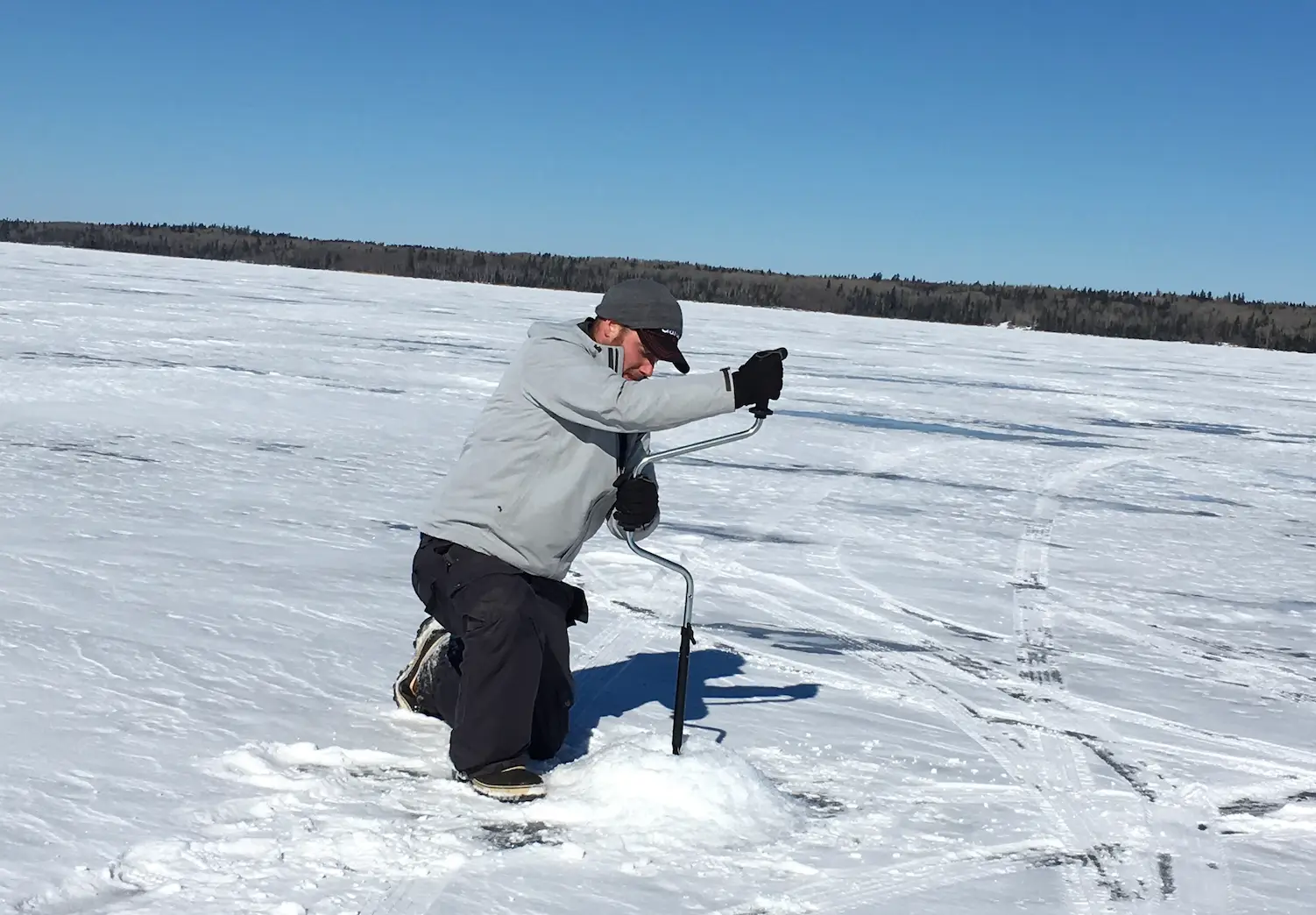 A man in the snow using a stick to take pictures.