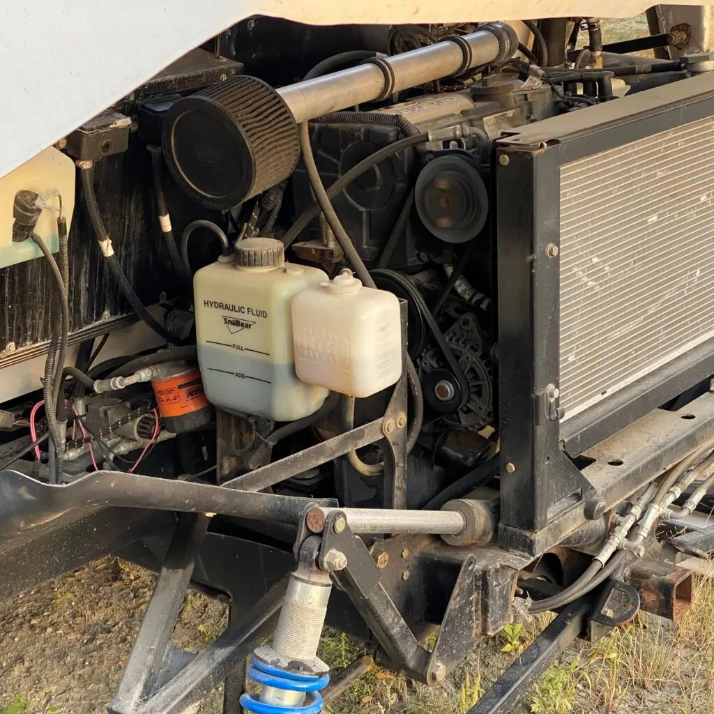 A truck with its hood up and the engine exposed.