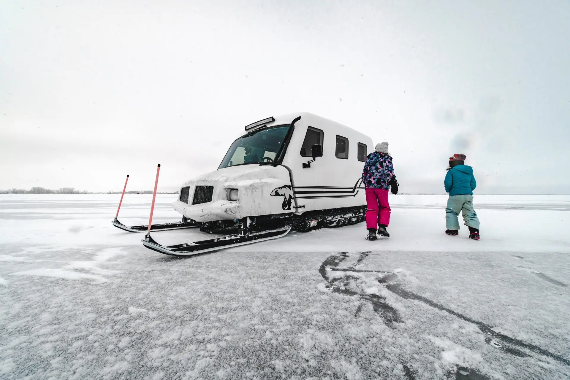 A person standing next to a snow vehicle.