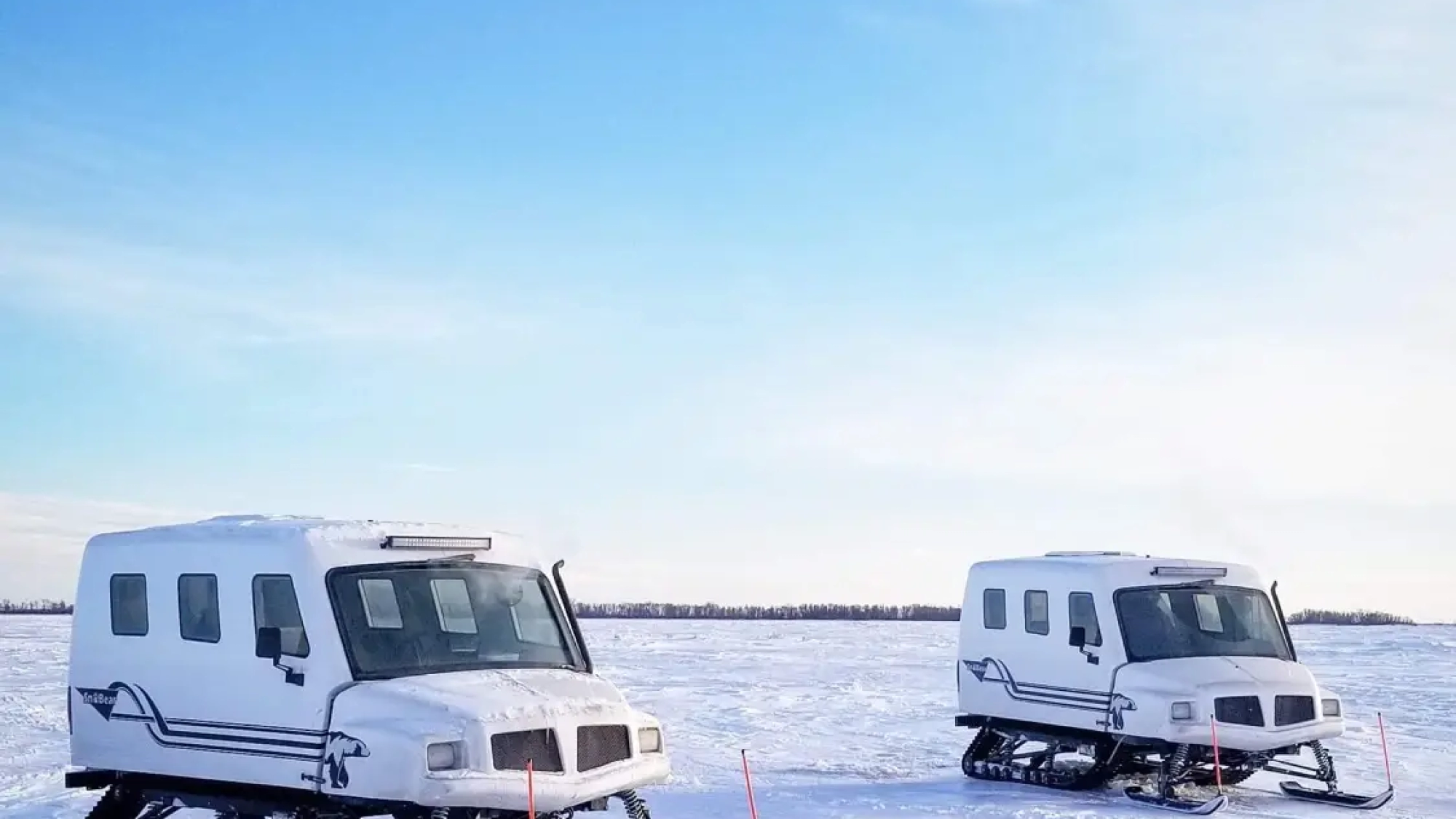 Two snowmobiles parked in the snow on a sunny day.