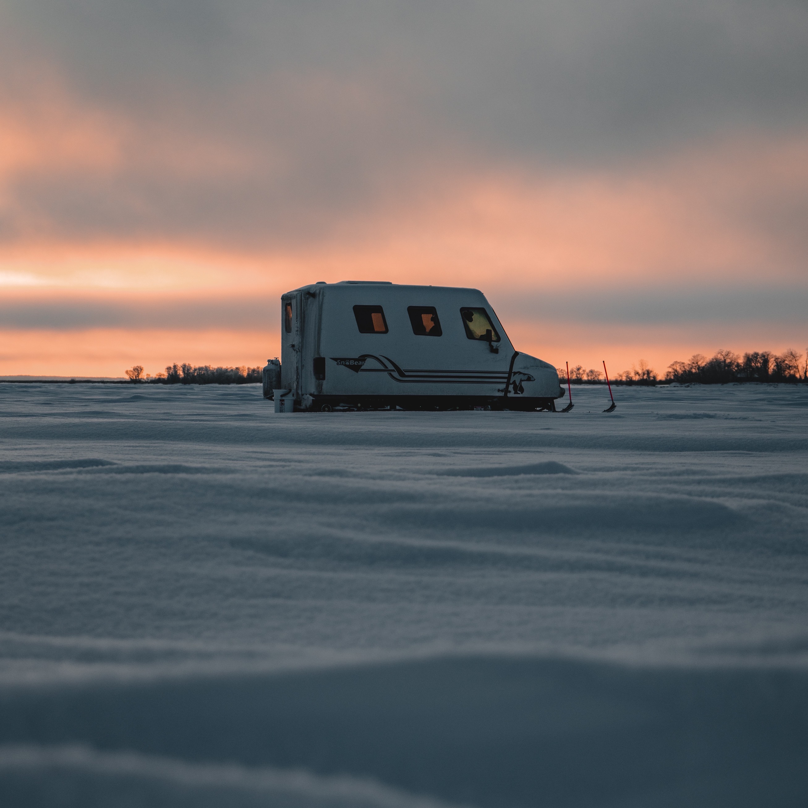 A small camper trailer is parked in the snow.