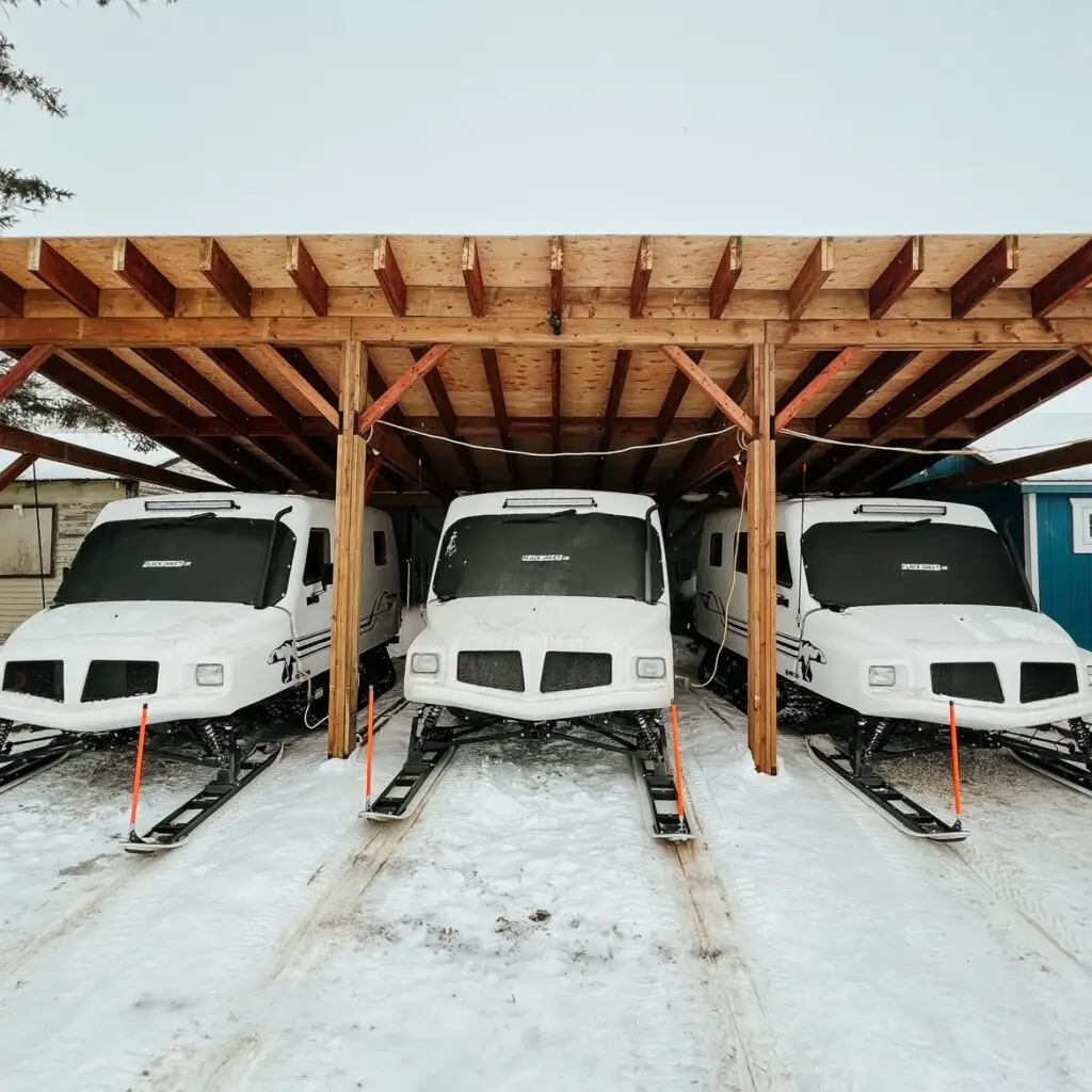 A group of three buses parked in the snow.