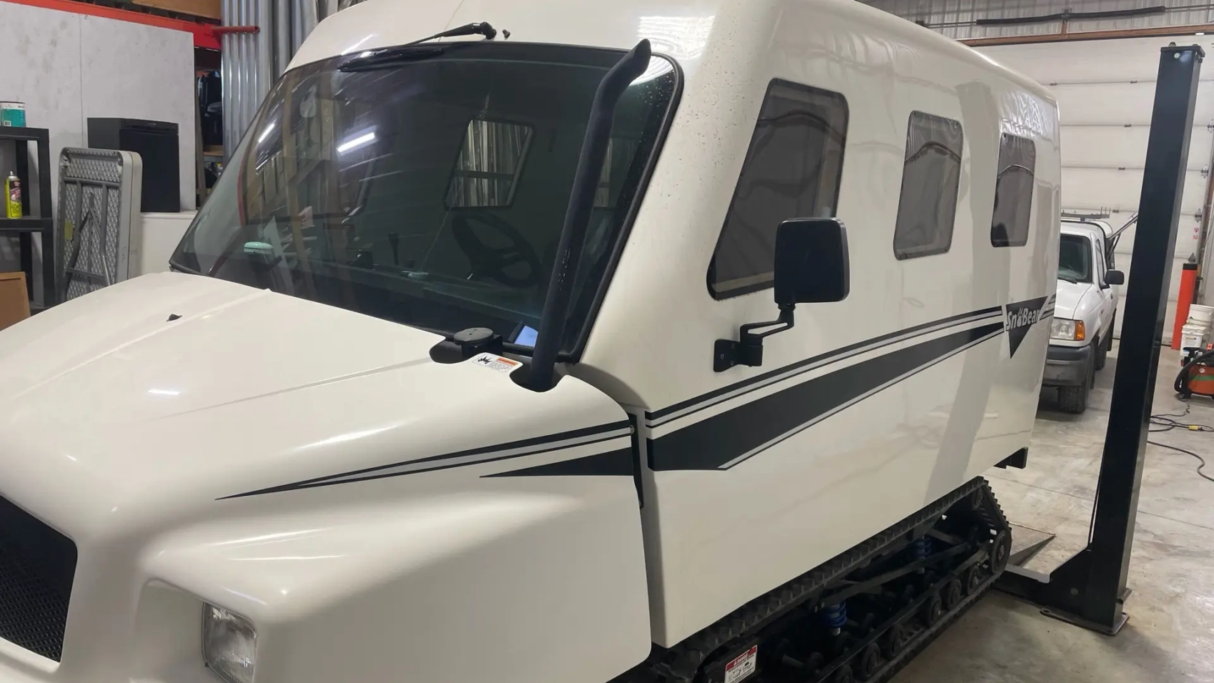 A white truck parked in a garage with other vehicles.