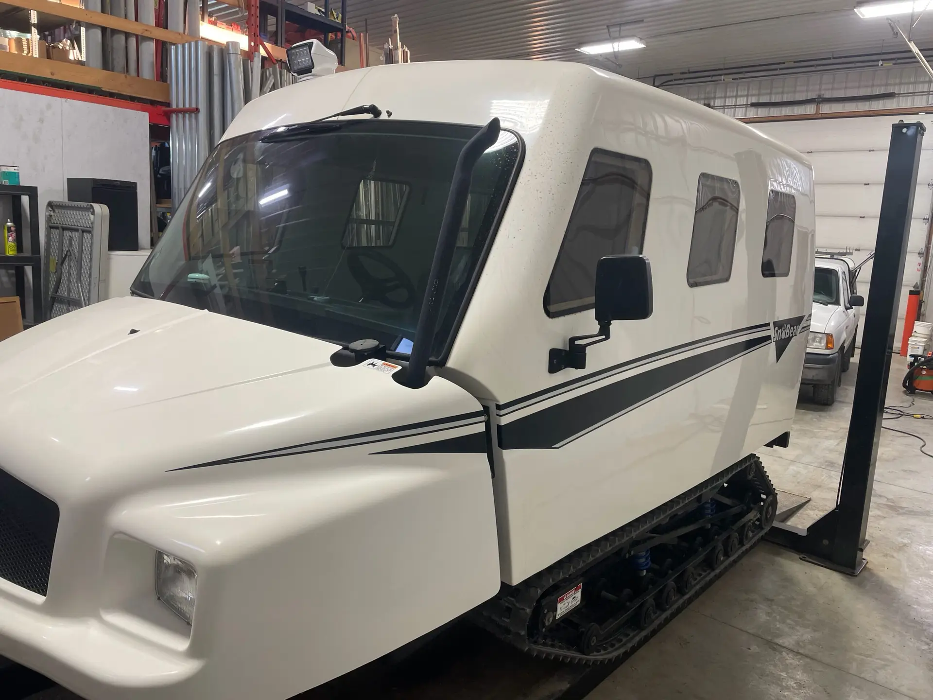 A white truck parked in a garage with other vehicles.