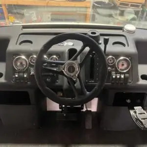 A steering wheel and dashboard of an old car.